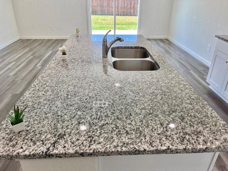 Kitchen with white cabinets, sink, a kitchen island with sink, light stone countertops, and wood-type flooring