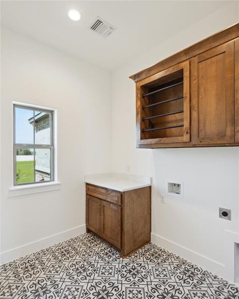 Clothes washing area featuring electric dryer hookup, washer hookup, cabinets, and light tile patterned floors