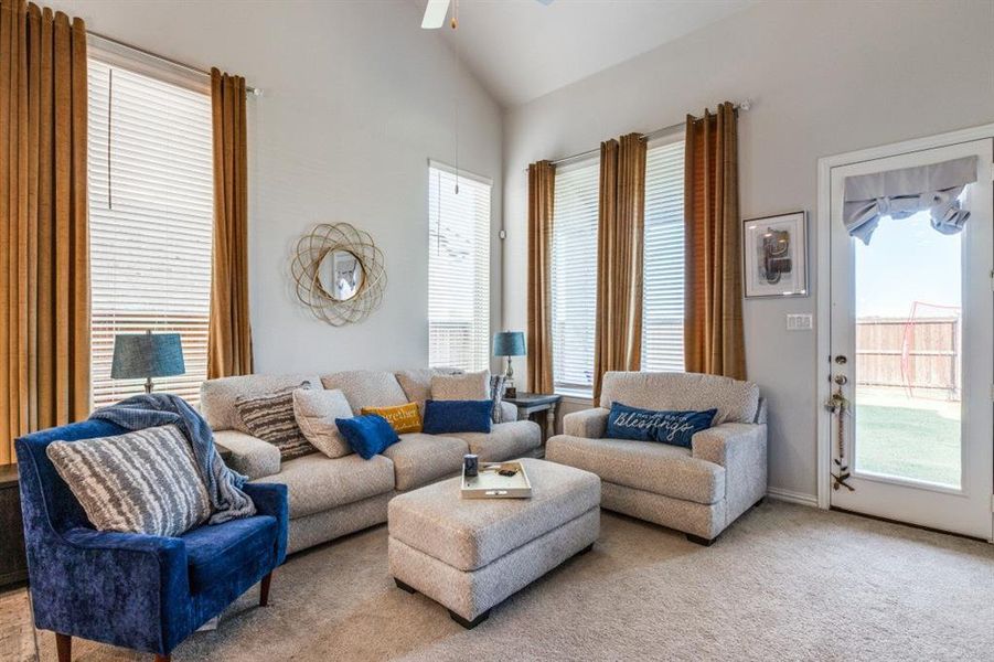 Living room with light carpet, a wealth of natural light, and vaulted ceiling