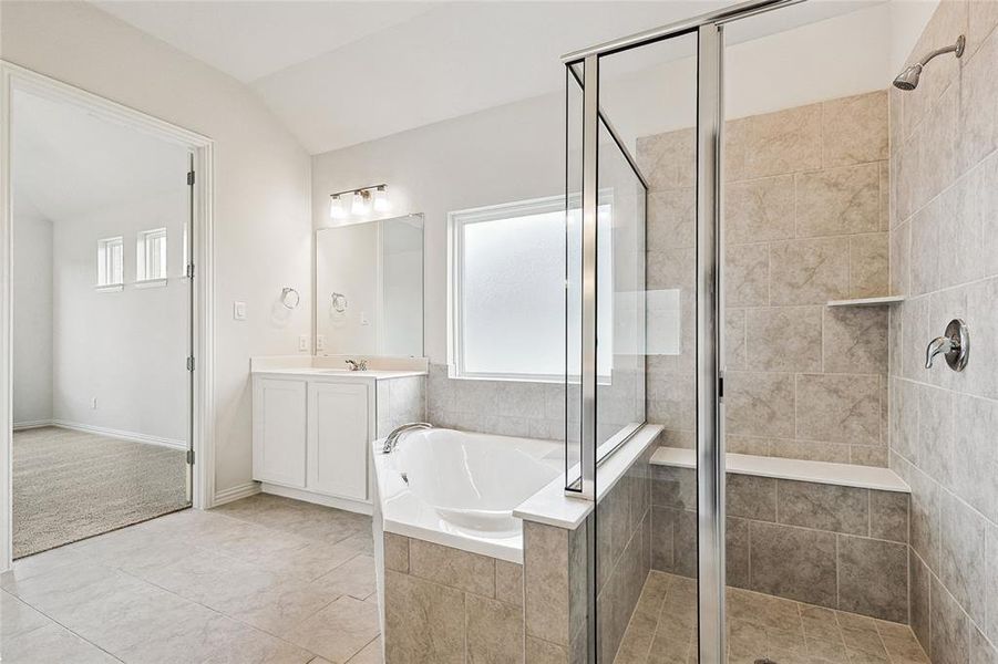 Bathroom with shower with separate bathtub, lofted ceiling, vanity, and tile patterned floors