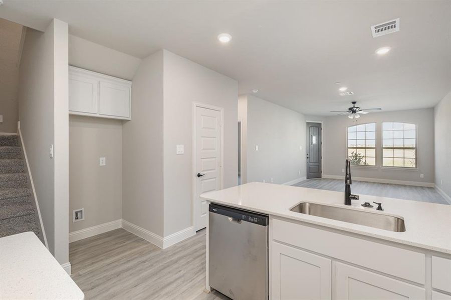 Kitchen with sink, dishwasher, white cabinets, and light hardwood / wood-style floors