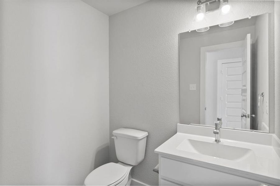 The half bathroom, conveniently situated on the 1st floor, is adorned with contemporary finishes. Light cabinets paired with a light countertop, custom wall paint, and sleek faucet combine to create a bright and inviting space. Sample photo of completed home. As-built color and selections may vary.