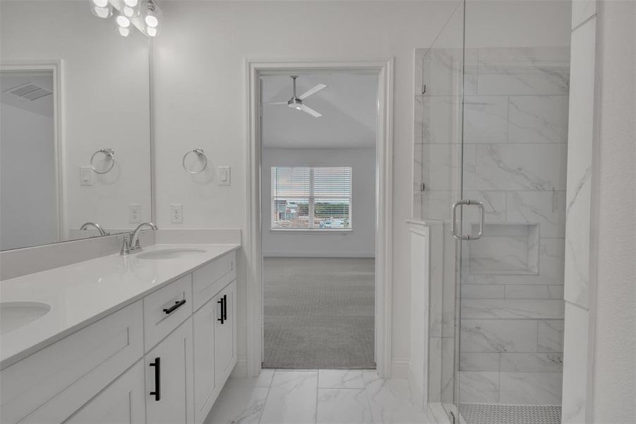 Bathroom with vanity with extensive cabinet space, ceiling fan, tile floors, a shower with shower door, and double sink