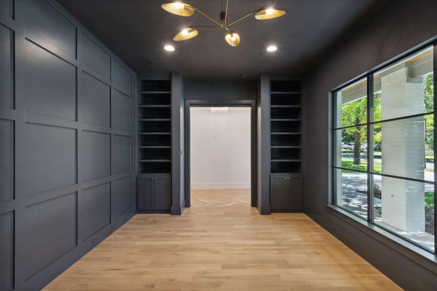 Spacious closet with light hardwood / wood-style floors and an inviting chandelier