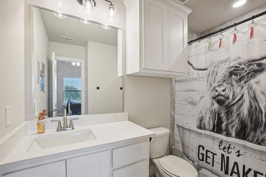 Bathroom featuring a shower with shower curtain, vanity, and toilet