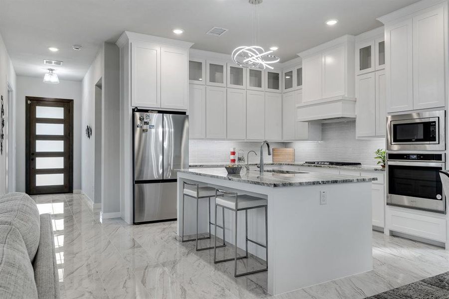 Kitchen featuring light tile patterned flooring, stainless steel appliances, backsplash, and a chandelier