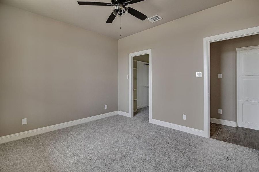 Unfurnished bedroom with a spacious closet, carpet floors, and ceiling fan
