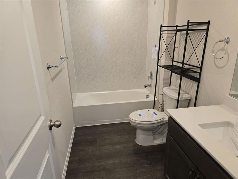 Full bathroom with wood-type flooring, shower / washtub combination, vanity, and toilet