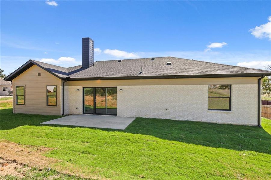 Rear view of house with a lawn and a patio area