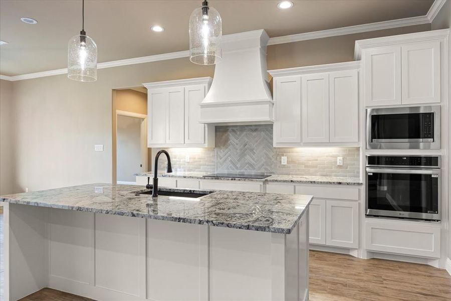 Kitchen with appliances with stainless steel finishes, pendant lighting, and white cabinetry