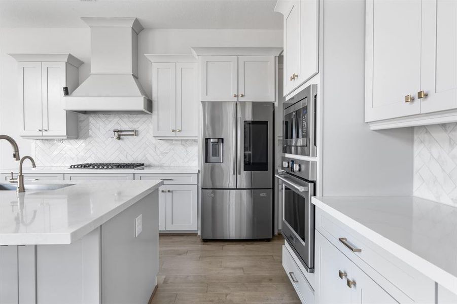 Step into this modern kitchen with light cabinets, beautiful chevron tile tying in the tile at the entry of the home, stainless steel appliances, upgraded large sink and plenty of storage from the uppers and lowers as well as storage in the island.