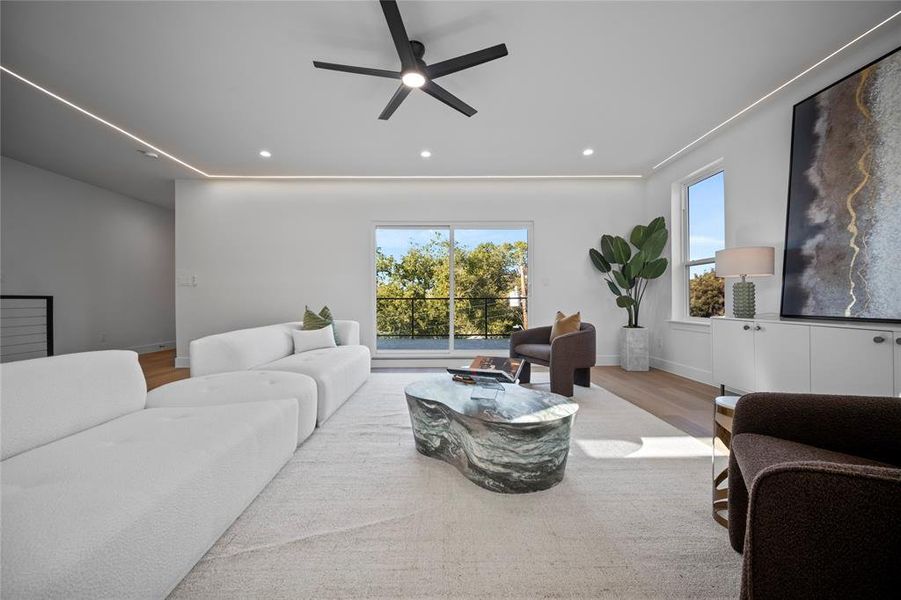 Living room with light hardwood / wood-style floors, a wealth of natural light, and ceiling fan