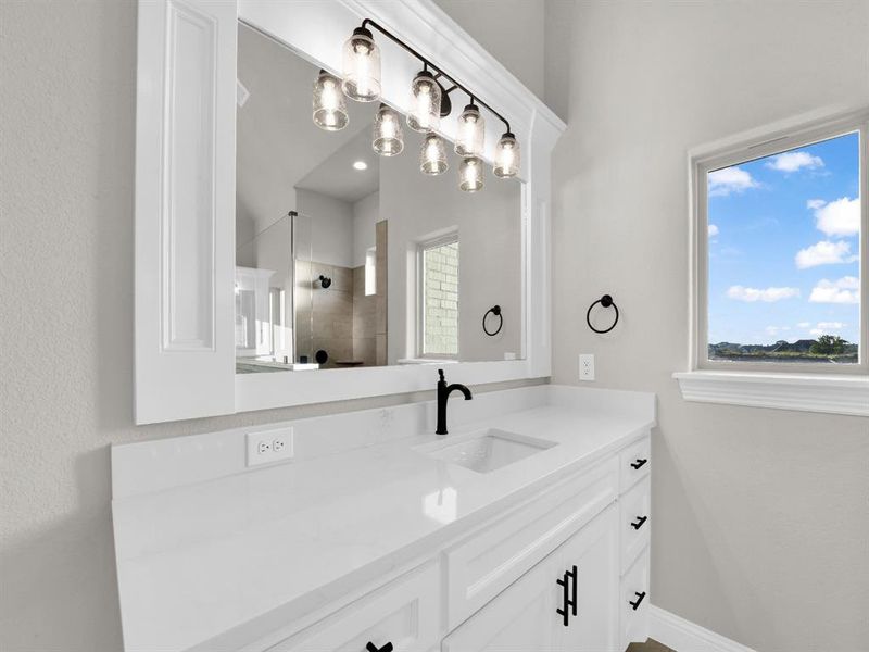 Bathroom with a healthy amount of sunlight, tiled shower, and vanity