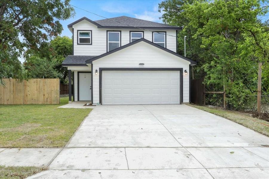 View of front of property featuring a front yard and a garage