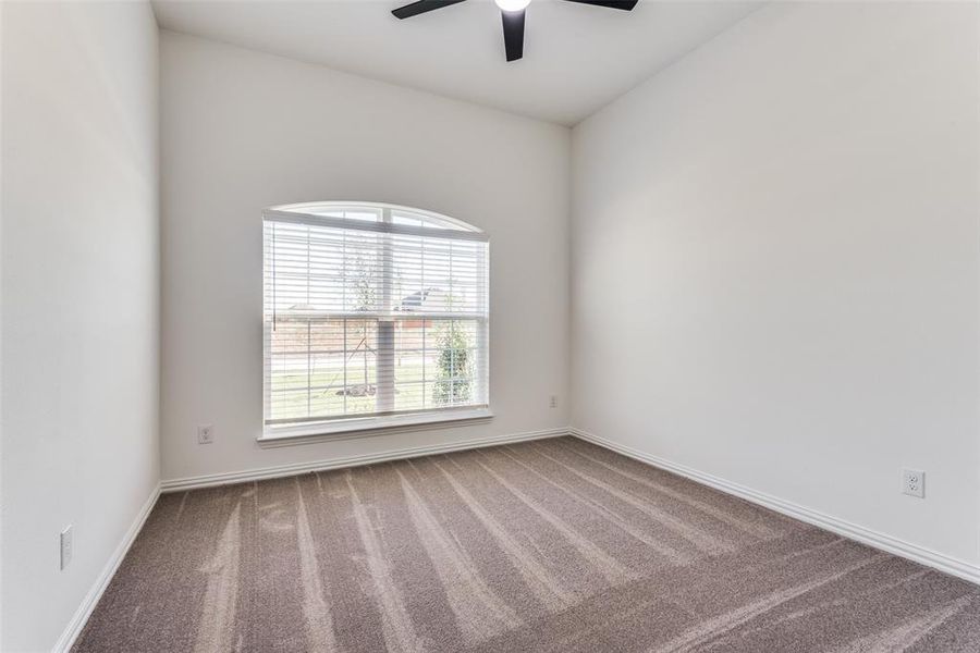 Carpeted empty room featuring ceiling fan