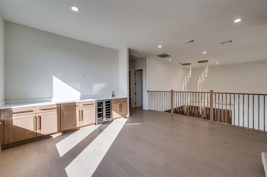 Empty room with wine cooler and light hardwood / wood-style floors