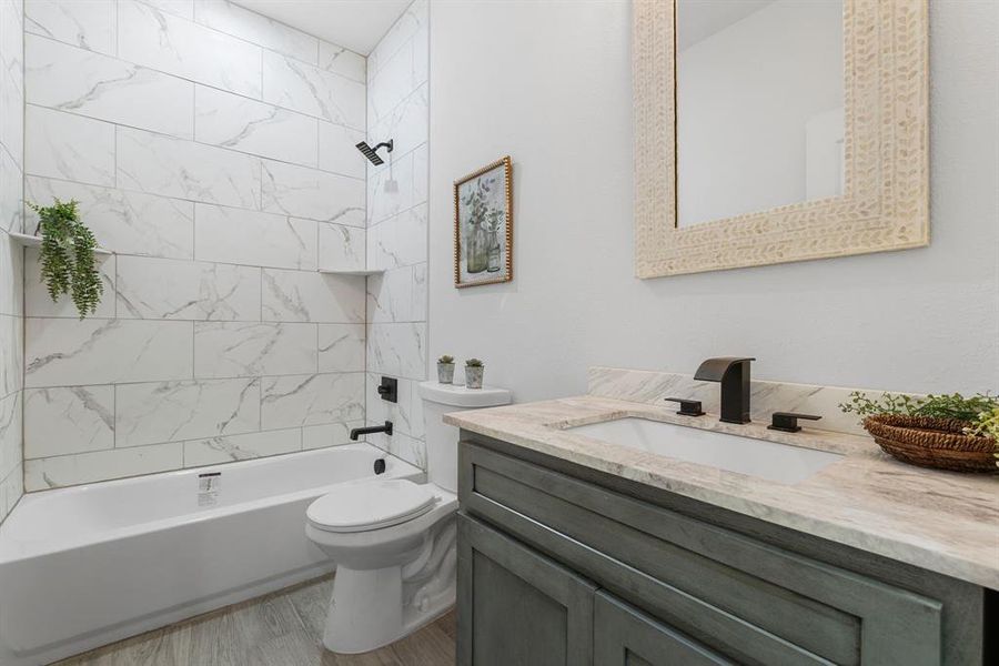 Full bathroom featuring vanity, tiled shower / bath combo, hardwood / wood-style flooring, and toilet
