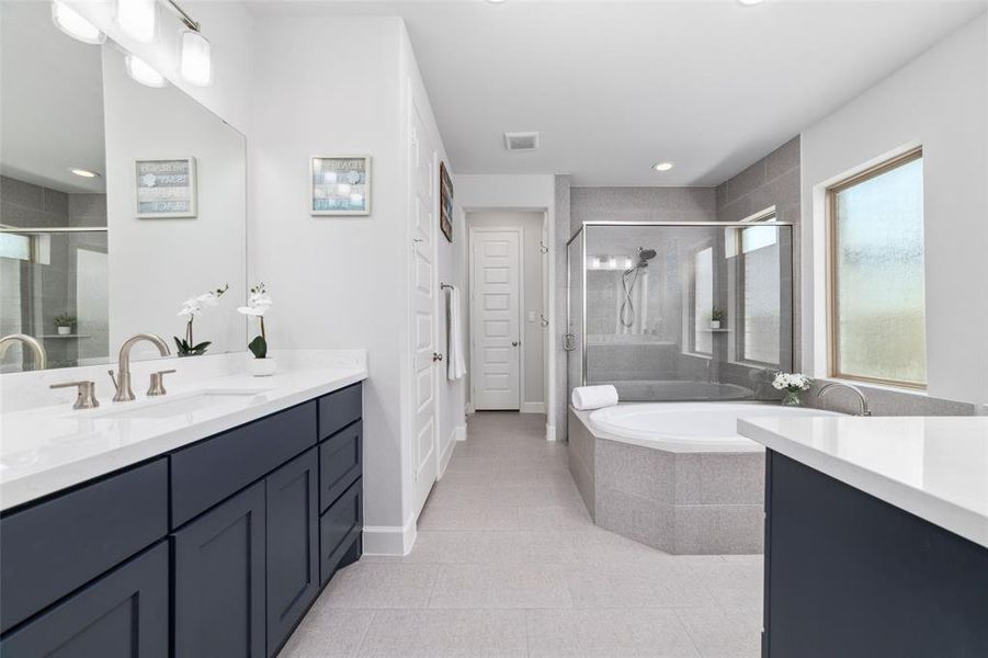You will love this spacious and modern bathroom featuring two Quartz vanities with navy blue cabinets, a garden bathtub, with a separate glass-enclosed shower.