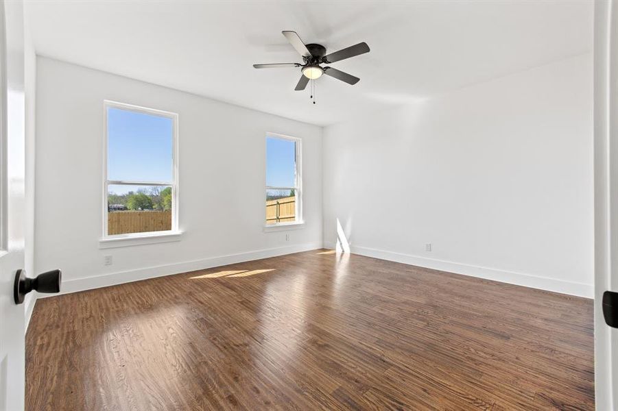 Unfurnished room featuring ceiling fan, a wealth of natural light, and dark hardwood / wood-style floors