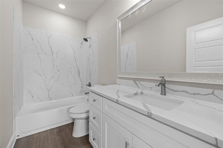 Full bathroom featuring toilet, hardwood / wood-style floors, vanity, and tiled shower / bath