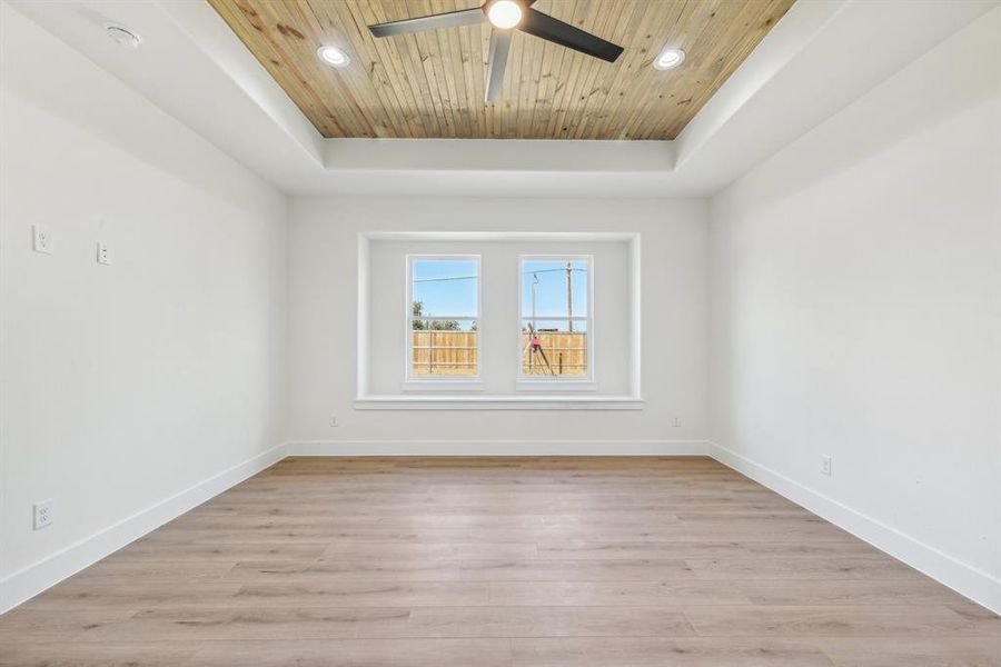 Unfurnished room with light hardwood / wood-style floors, a raised ceiling, ceiling fan, and wood ceiling