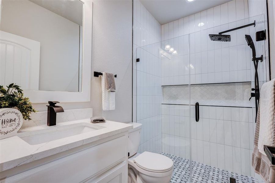 Guest bathroom featuring walk in shower, tile patterned flooring, toilet, and vanity