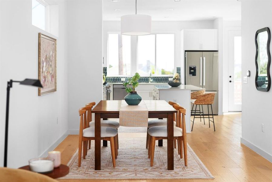 Airy dining area with hardwood floors and abundant natural light from large windows.