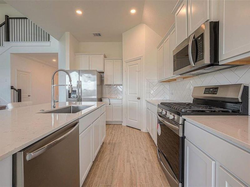 This kitchen is ideal for hosting gatherings. The ample counter space allows for easy food preparation, while the breakfast bar provides seating for guests.