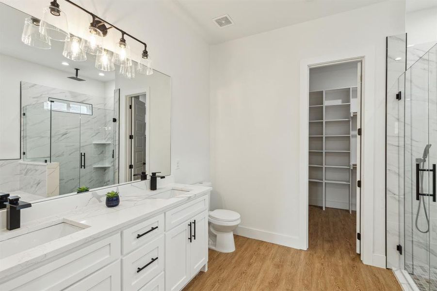 Bathroom with wood-type flooring, dual vanity, an enclosed shower, and toilet