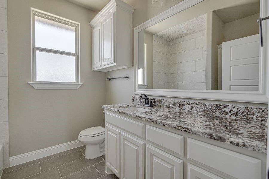 Bathroom featuring vanity, toilet, and tile patterned flooring