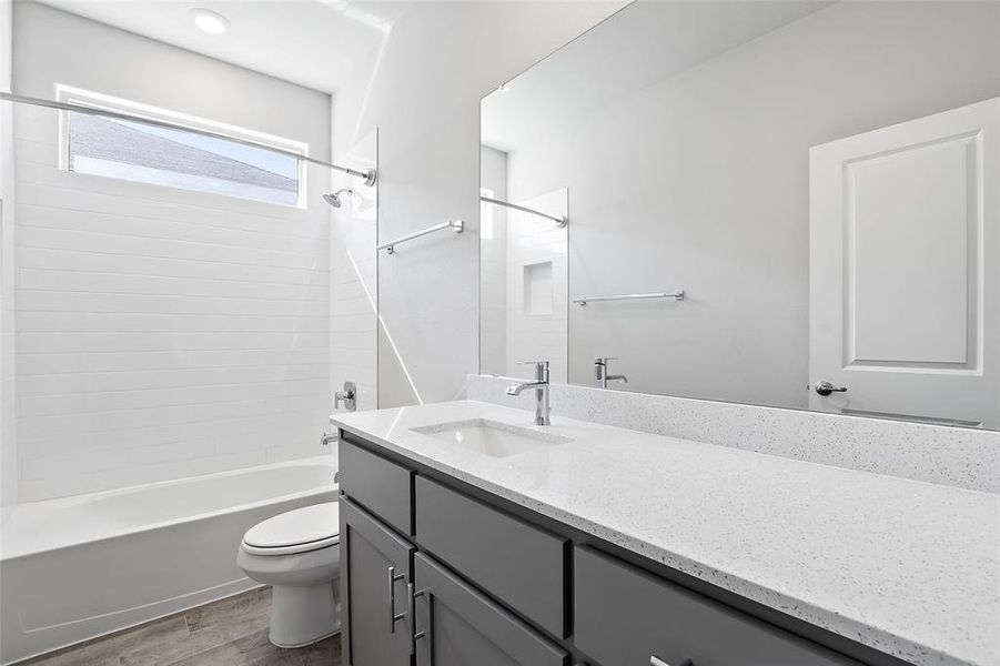 Full bathroom with toilet, tiled shower / bath, hardwood / wood-style flooring, and vanity