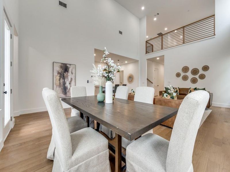 Dining space featuring a towering ceiling, a chandelier, and light hardwood / wood-style floors