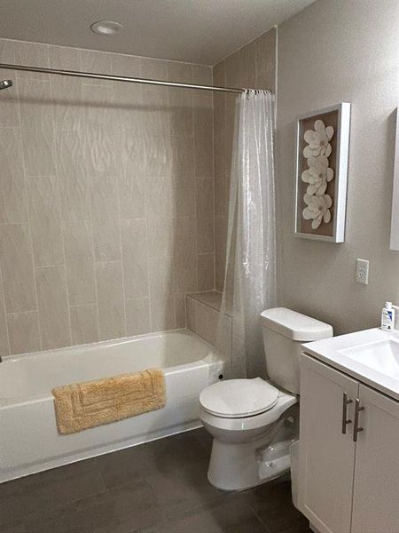 Full bathroom featuring vanity, shower / tub combo, and toilet