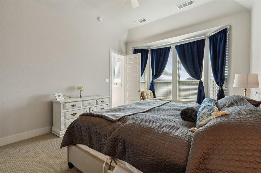 Primary bedroom featuring bumped out bay windows overlooking the backyard and ceiling fan.