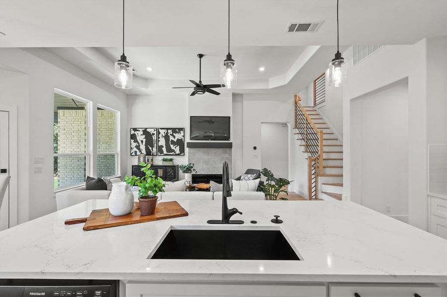 Kitchen featuring a center island with sink, sink, light stone countertops, and a fireplace