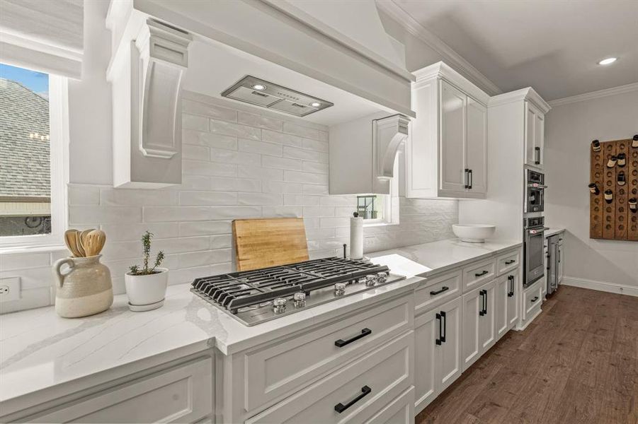 Kitchen with white cabinetry, backsplash, dark wood-type flooring, and light stone countertops