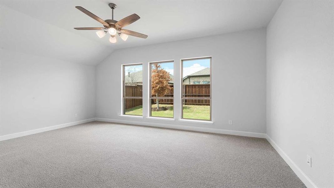 Carpeted empty room featuring lofted ceiling and ceiling fan