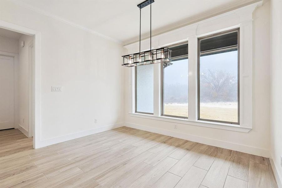 Unfurnished dining area with an inviting chandelier, light hardwood / wood-style floors, and ornamental molding