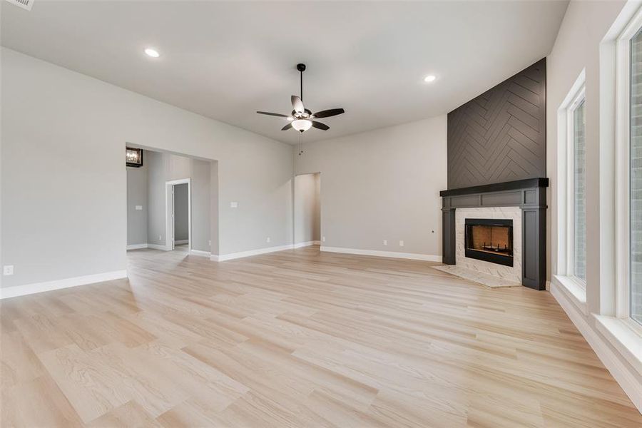 Unfurnished living room featuring ceiling fan, light wood-type flooring, and a tile fireplace