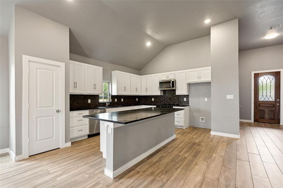 Kitchen with a wealth of natural light, appliances with stainless steel finishes, and white cabinetry