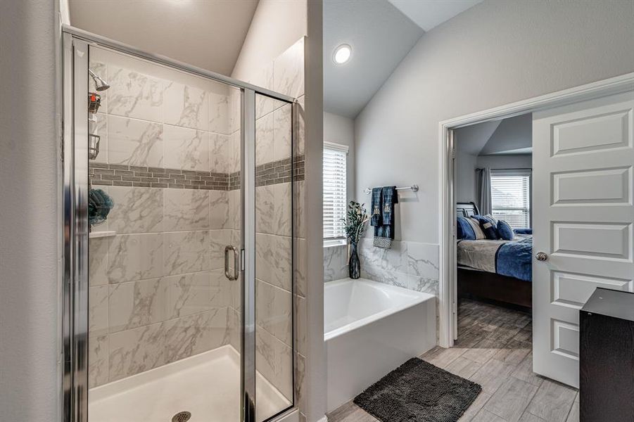 Bathroom featuring vaulted ceiling, separate shower and tub, and hardwood / wood-style floors