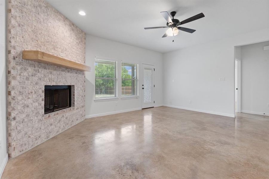 Unfurnished living room with ceiling fan and a brick fireplace