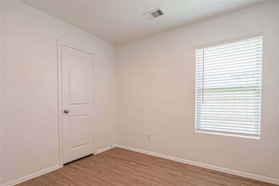 This guest bedroom features a large window that fills the cozy room with light.