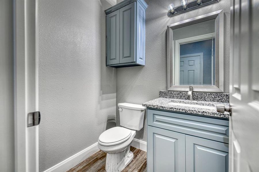 Bathroom with large vanity, wood-type flooring, and toilet