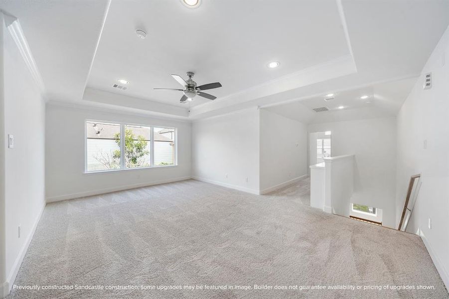 Let the fun begin in this vibrant game room, with a tray ceiling, ceiling fan, and a wall of windows flooding the space with light.