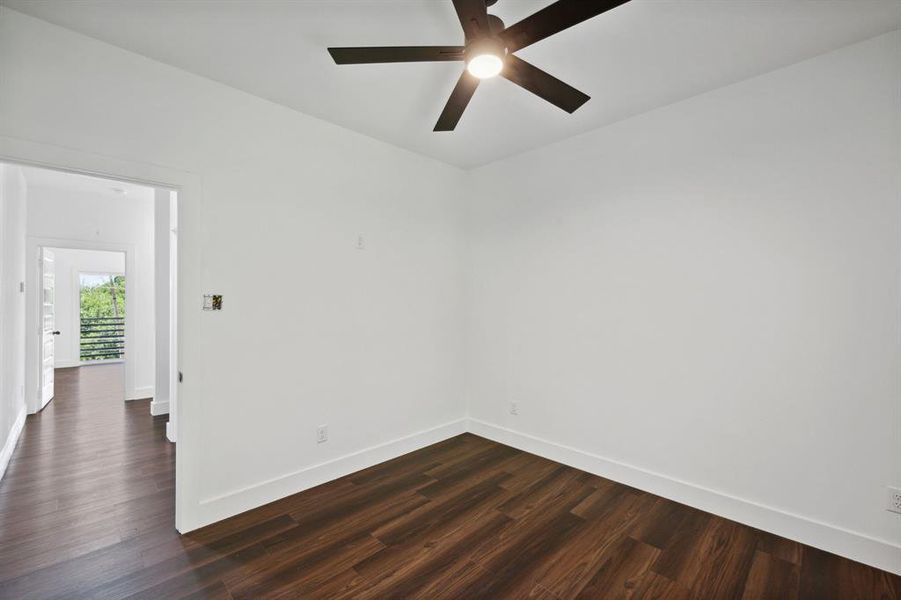 Spare room featuring dark wood-type flooring and ceiling fan