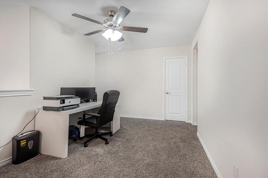 Carpeted office featuring ceiling fan