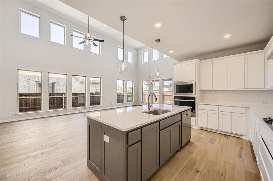 Kitchen with sink, white cabinetry, stainless steel appliances, and light wood-type flooring