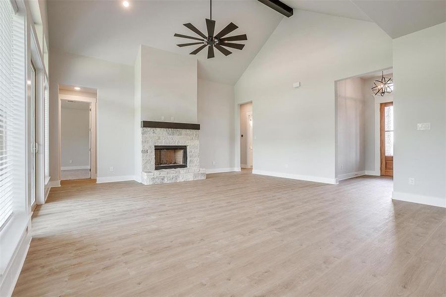 Unfurnished living room featuring beam ceiling, light hardwood / wood-style floors, and high vaulted ceiling