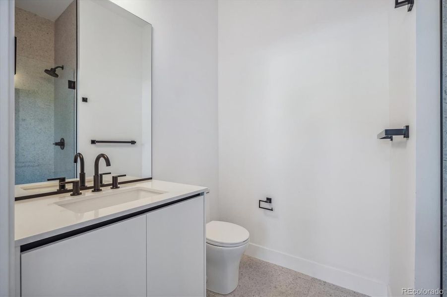 En-Suite to Lower-Level Secondary Bedroom Featuring Modern Tile, Finishes and Fixtures.